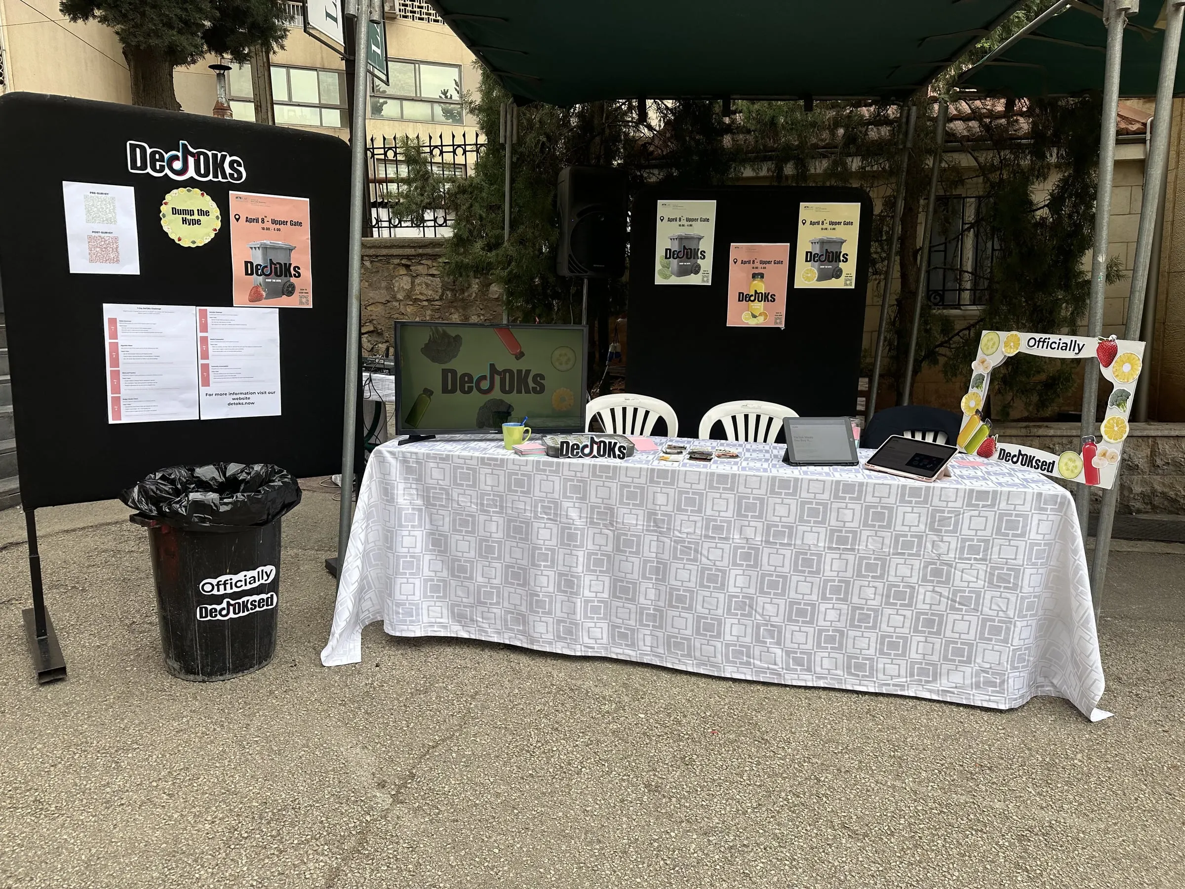 The DeTOKs booth at LAU’s Upper Gate: posters, a table with tablets and the “Officially DeTOKsed” regret bin.